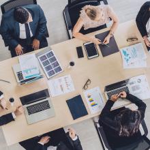 Vista aérea de una mesa de reuniones en que hay varias personas con ordenadores portátiles, debatiendo la respuesta ante un incidentes de seguridad digital.