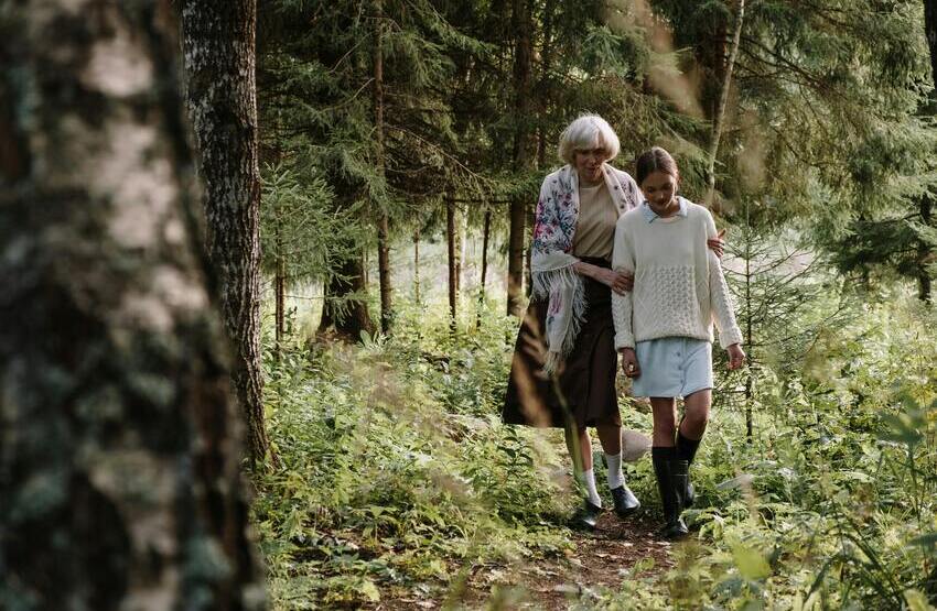 Mujer mayor y niña paseando por un bosque